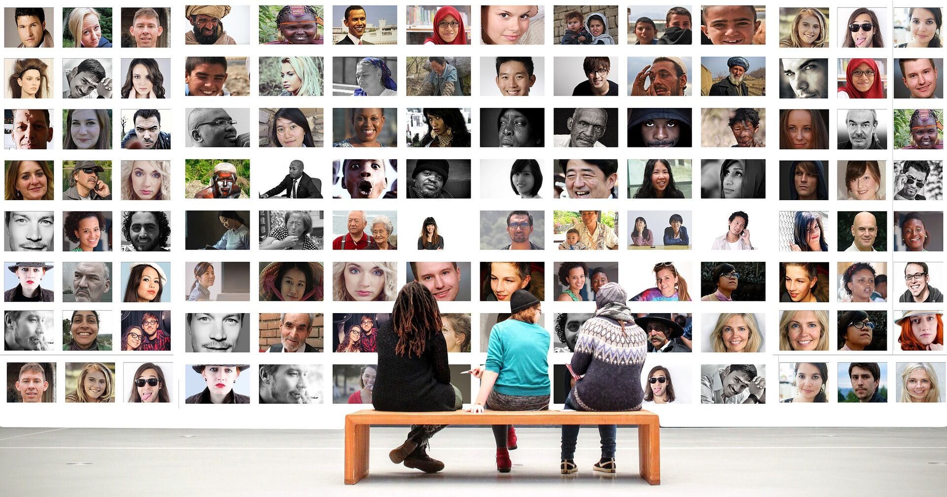 Drei Menschen sitzen vor einer Wand, welche aus vielen verschiedenen Fotos von Menschen besteht